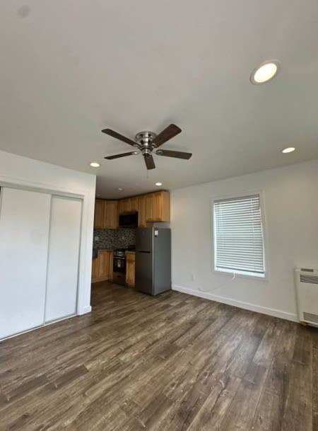 A room with a ceiling fan and wooden flooring.